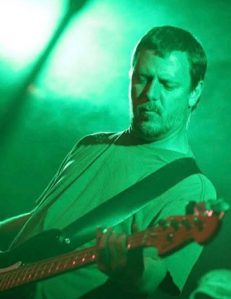 Mark Moffatt performing live under green stage lights — The Glorious Heydays
